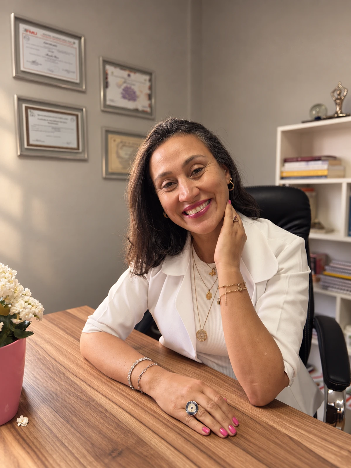 Alessandra Muniz sorrindo, sentada à mesa do seu consultório.